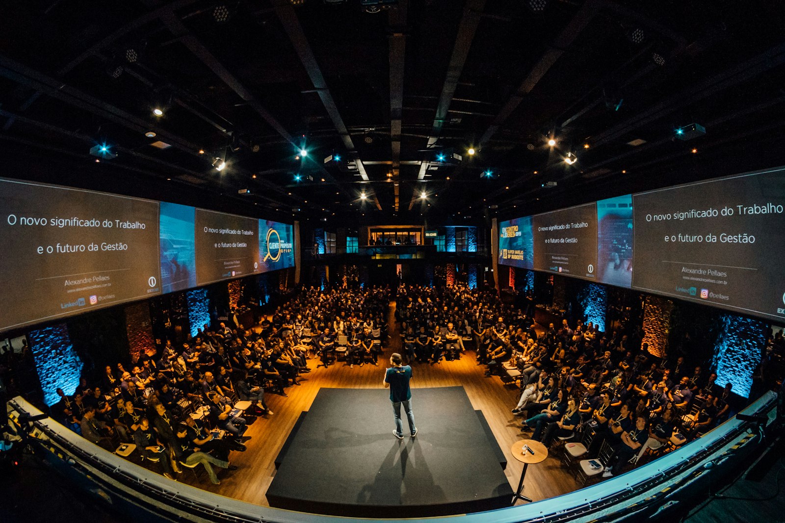 Speaker on a large stage in a fully occupied auditorium