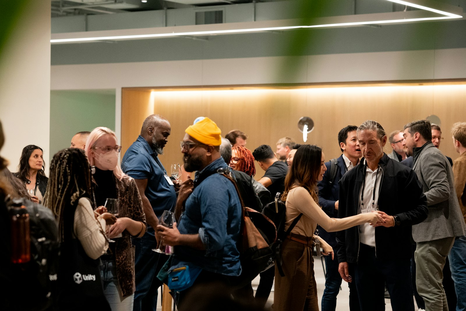 Conference attendees networking and shaking hands at a warm-lit indoor event