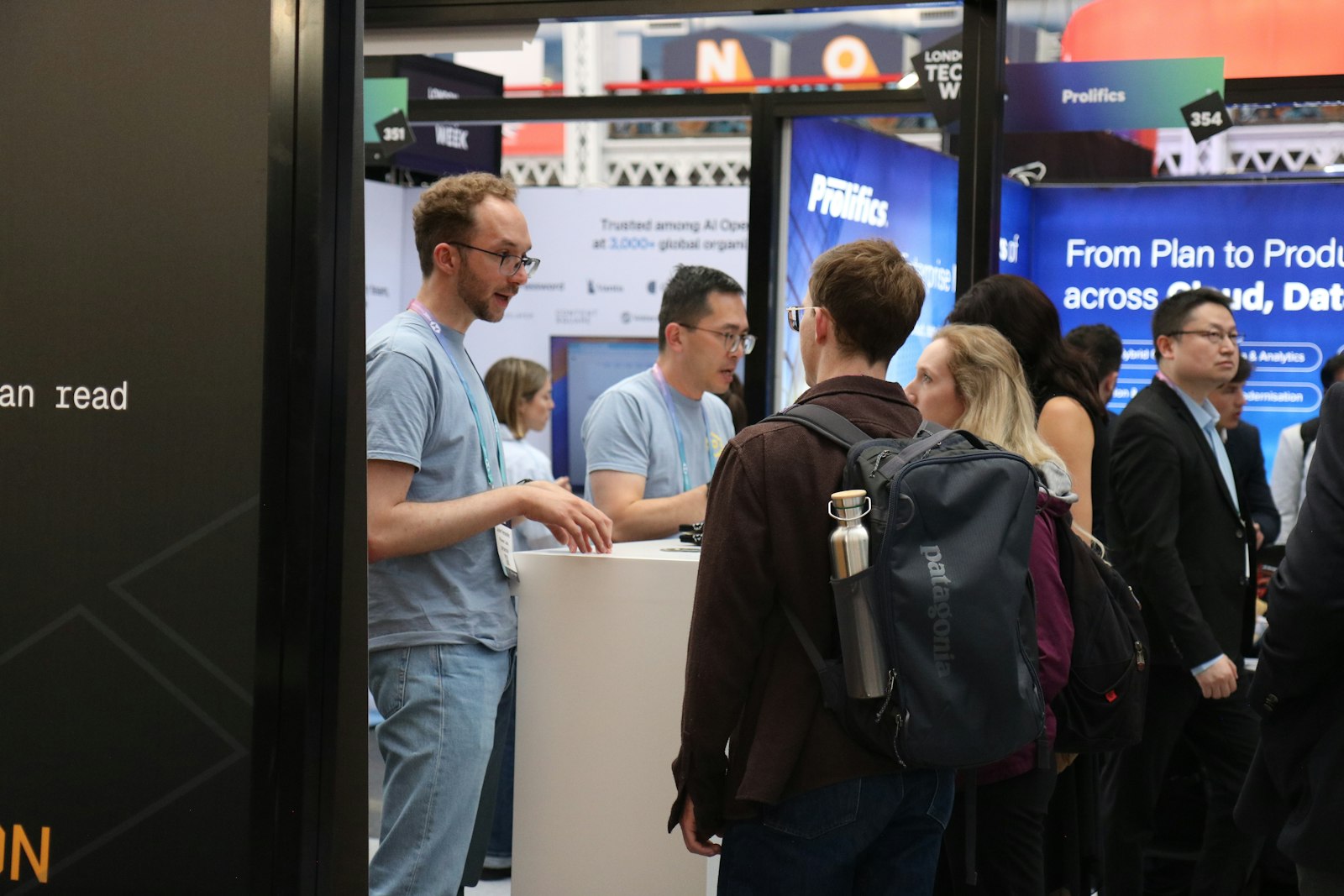 Booth staff showing a visitor a QR code on a smartphone at a modern exhibition stand